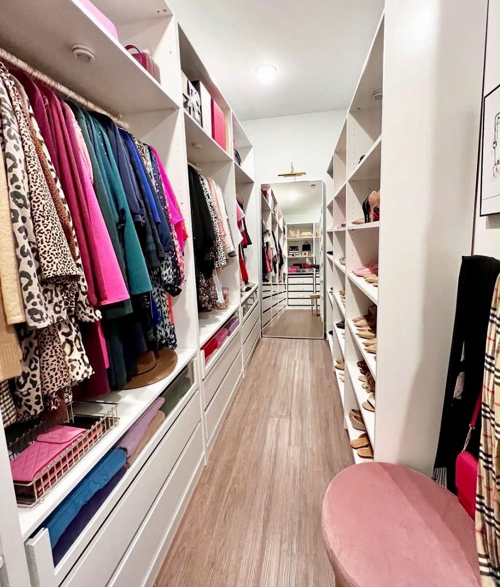Long walk-in closet with color-sorted clothes